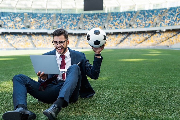 Man on laptop sitting in football stadium