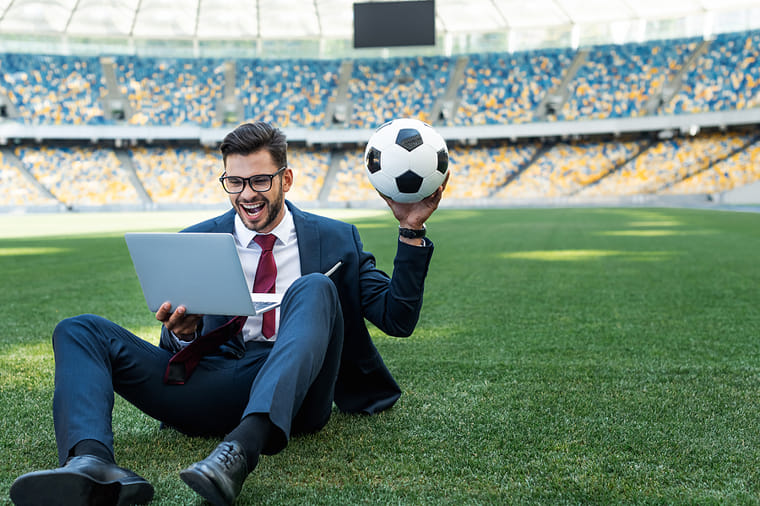 Man on laptop in football stadium